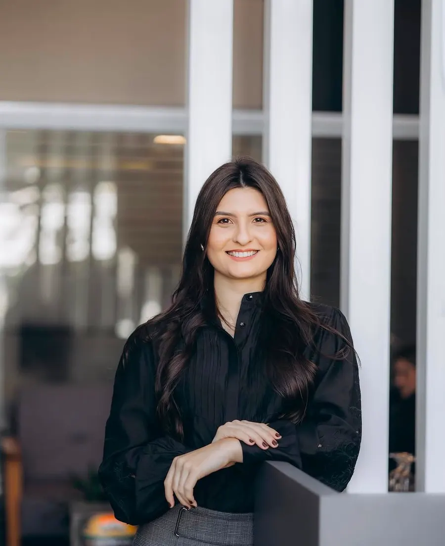 Sylvia Duarte, advogada, de blusa preta, sorrindo no escritório